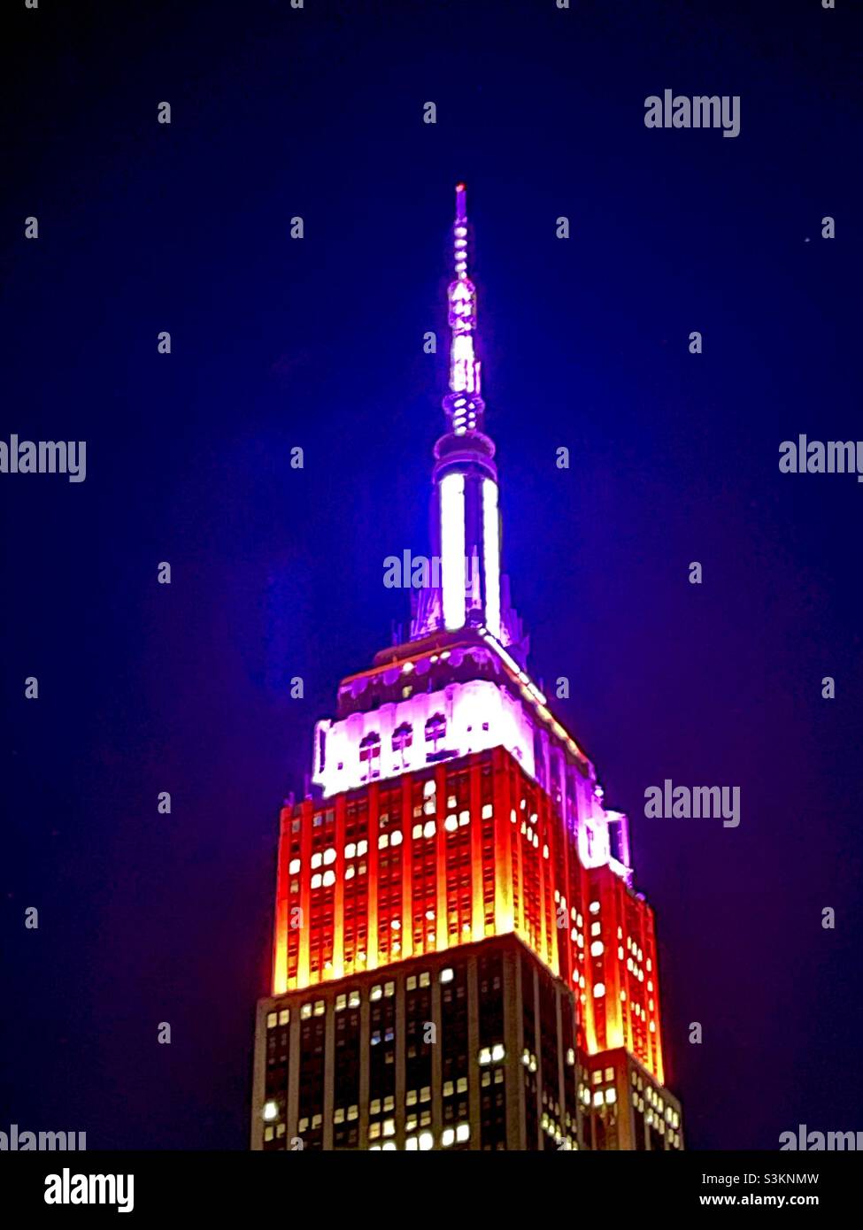 The Tower Lights on top of the Empire State Building glow red & purple in honor of the Lupus Research Association. - Smartphone Captured Stock Image