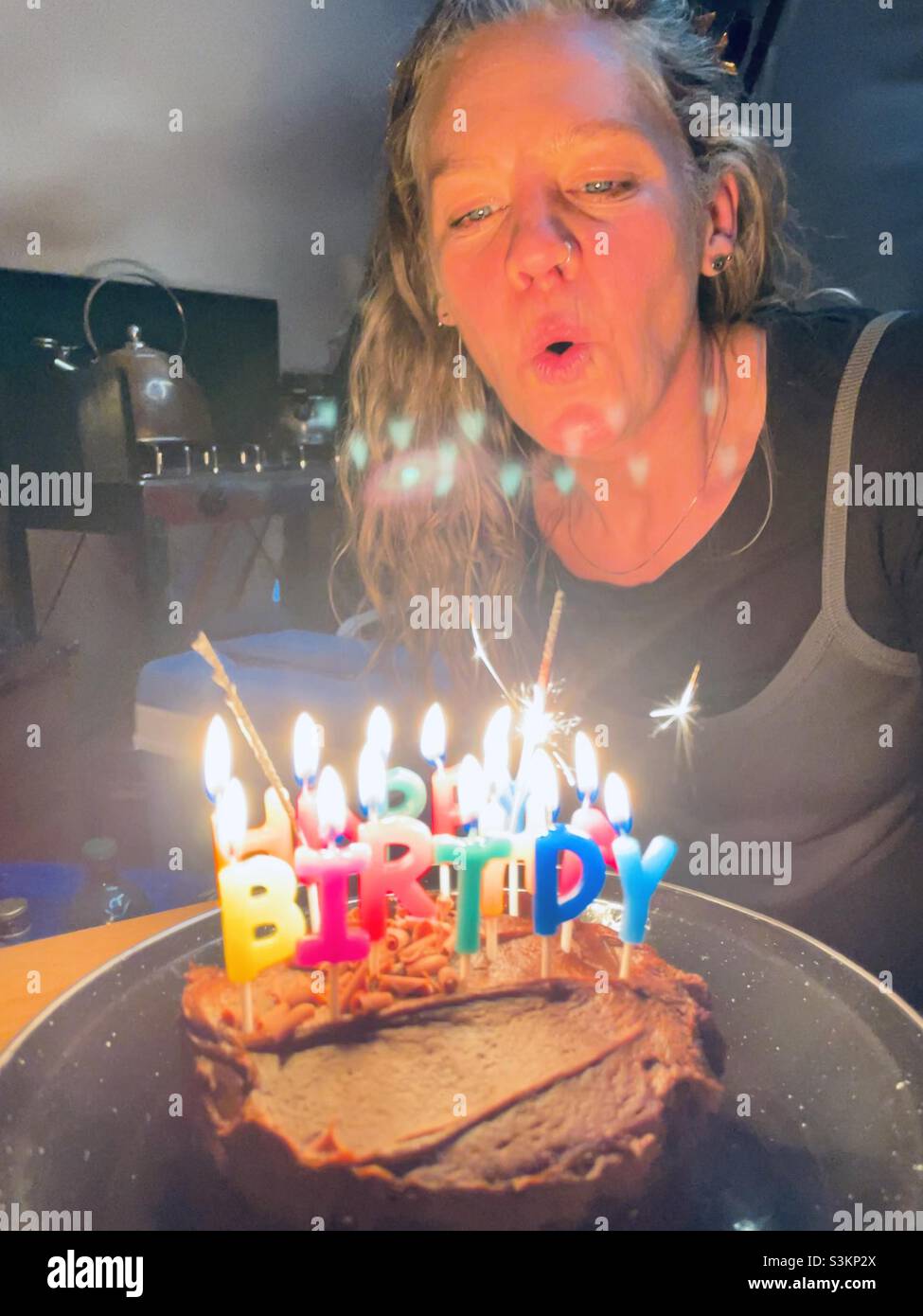 A woman blows out candles on a birthday cake in a tent in Wales Stock Photo