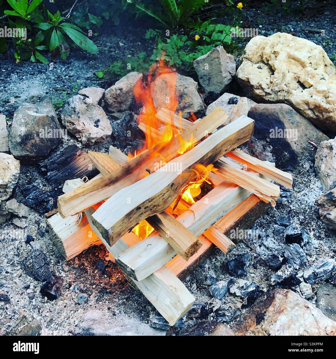 A neatly stacked campfire with wood arranged to allow good airflow - Smartphone Captured Stock Image