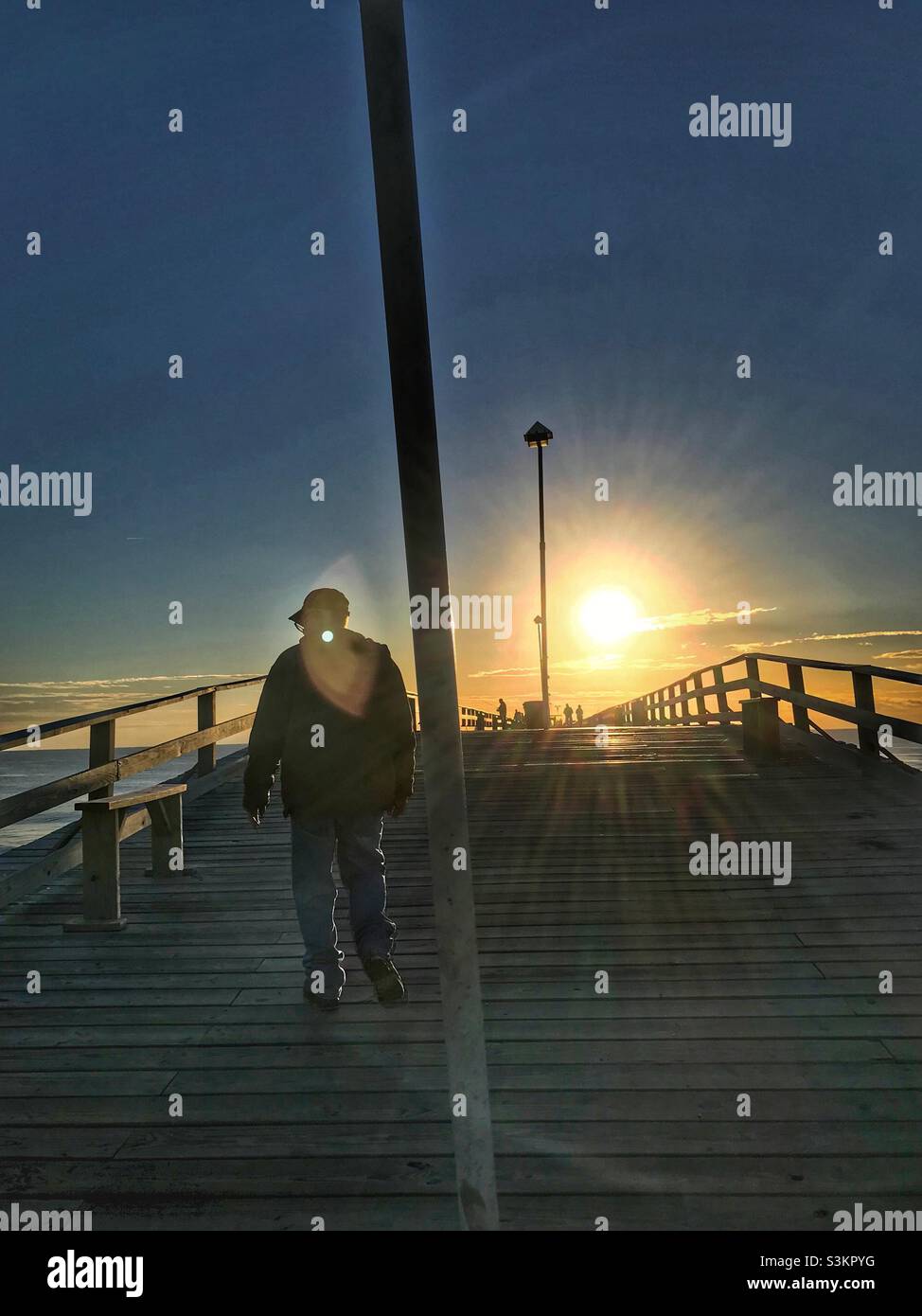 Man walks down fishing pier in November sunrise. Kure Beach - Smartphone Captured Stock Image