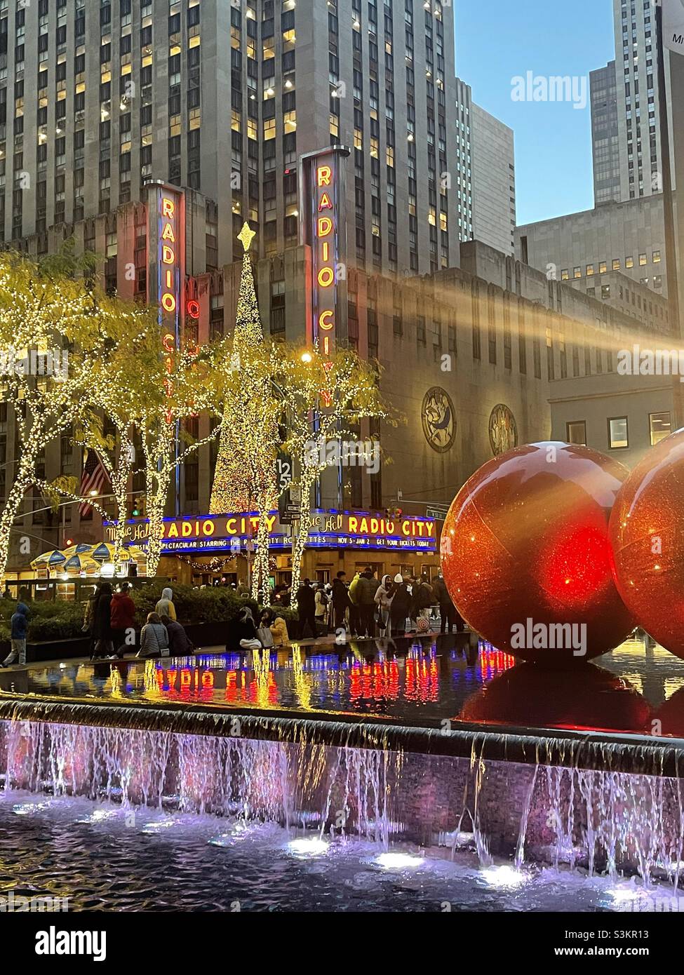 During the holiday season giant Christmas tree ornaments are piled high and reflecting pool across from the radio city music Hall, 2021, New York City, United States - Smartphone Captured Stock Image