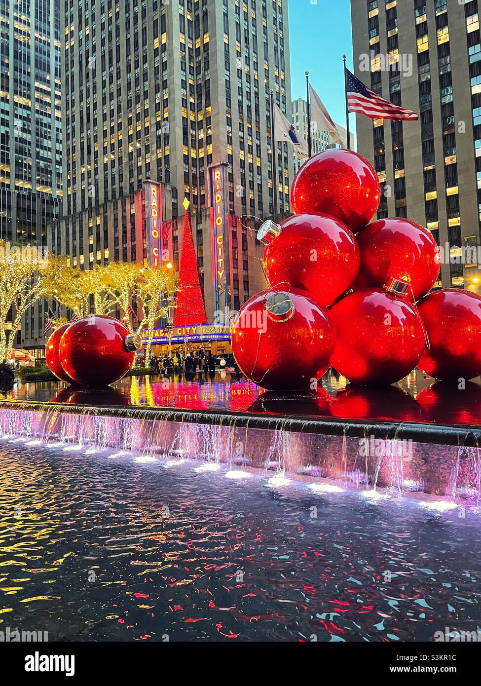 During the Christmas season giant ornaments are piled high and brightly lit across from radio city music Hall in Midtown Manhattan, 2021, New York City, United States - Smartphone Captured Stock Image