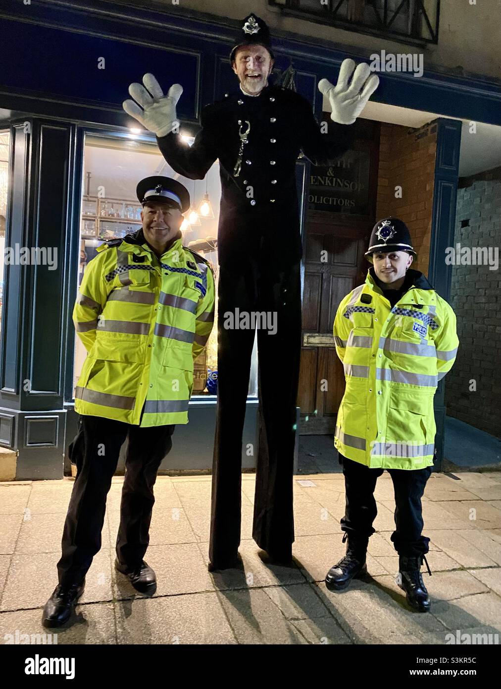 Three smiling policemen. One of the policemen is on stilts and dressed in Victorian clothes for the Victorian evening in Warwick town centre. Stock Photo