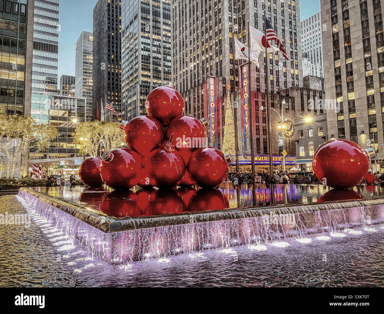 2021, giant Christmas tree ornaments are piled high and brightly lit in a reflecting pool across from the radio city music Hall on a cold holiday evening, New York City, United States - Smartphone Captured Stock Image