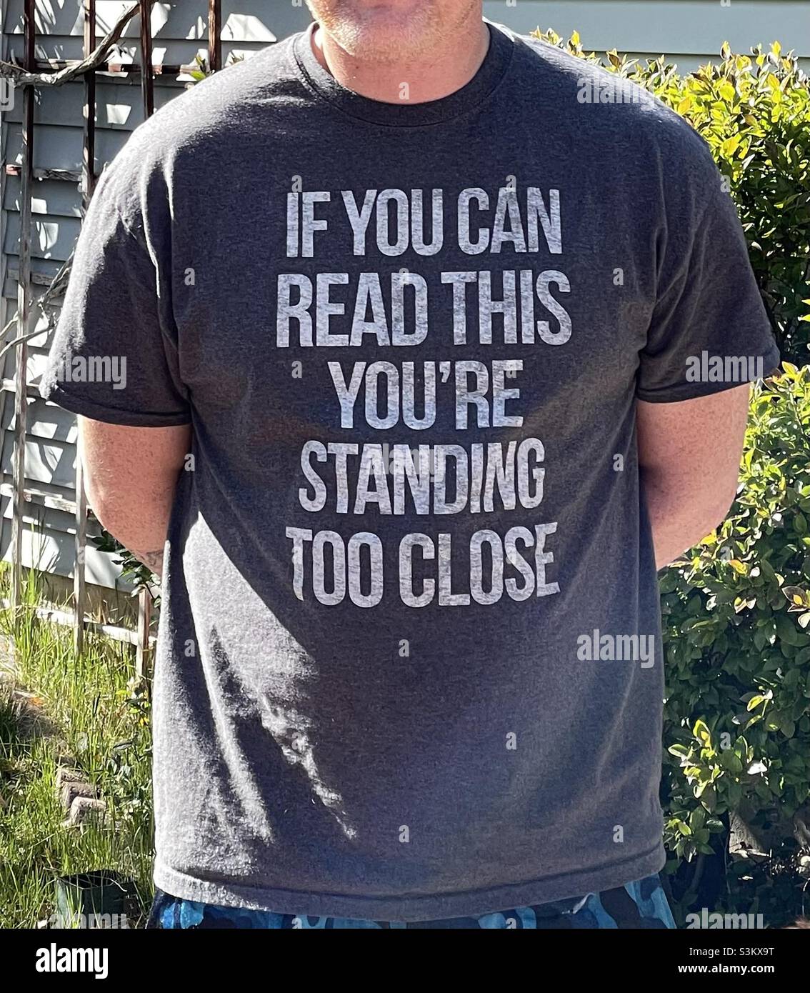 Man dressed casually wearing a snarky and humorous t-shirt that warns people not to stand too close. - Smartphone Captured Stock Image