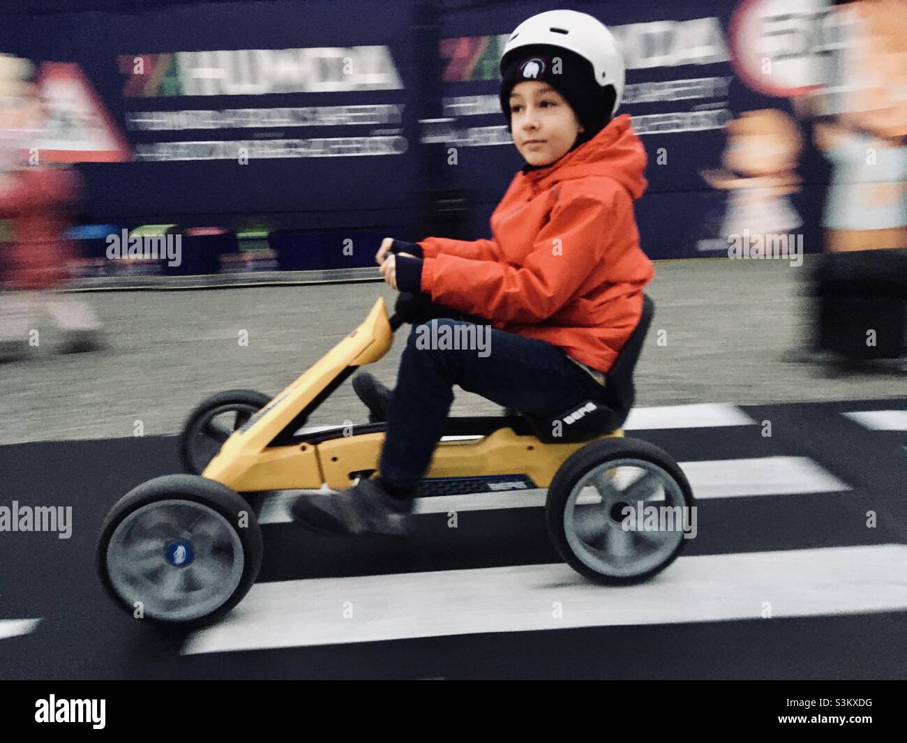 Boy child riding on pedal go kart with safety helmet - Smartphone Captured Stock Image