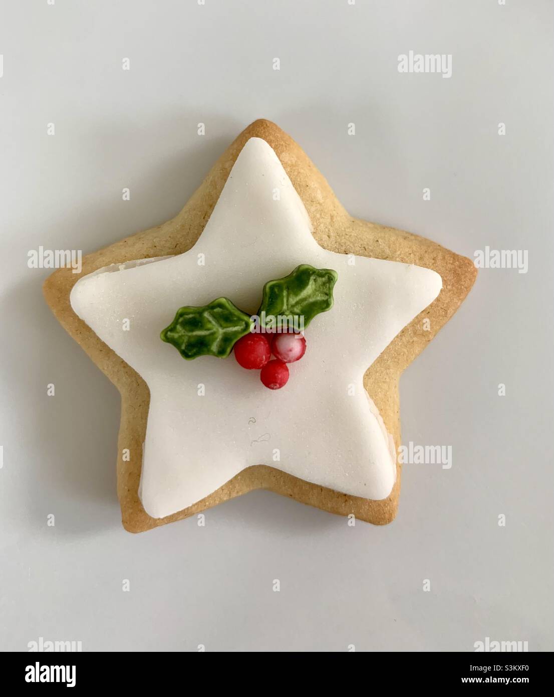 Homemade Christmas iced star biscuit with holly decorations Stock Photo