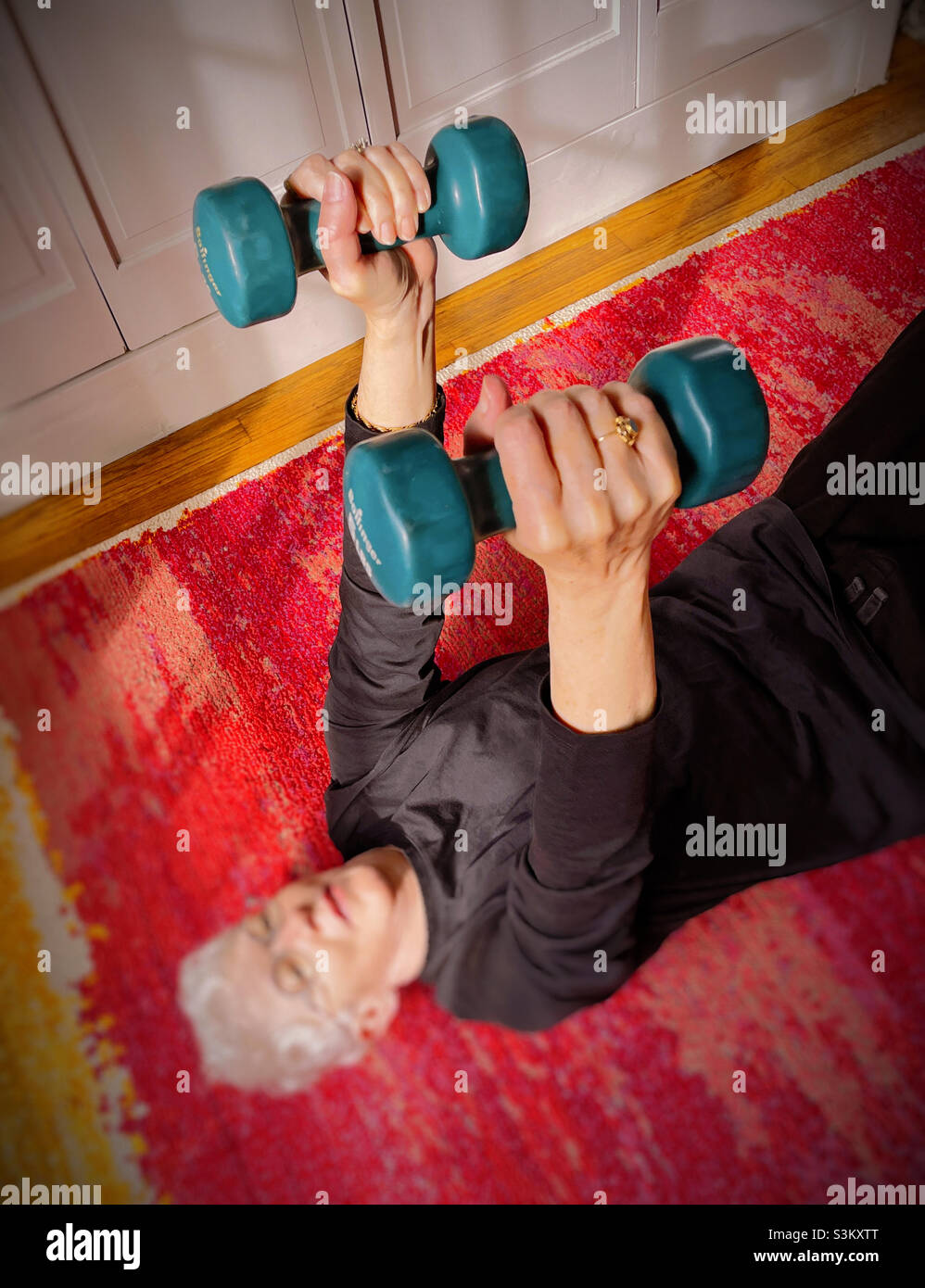 Senior Woman exercising at home with 5 pound  barbell in each hand, 2021, USA - Smartphone Captured Stock Image
