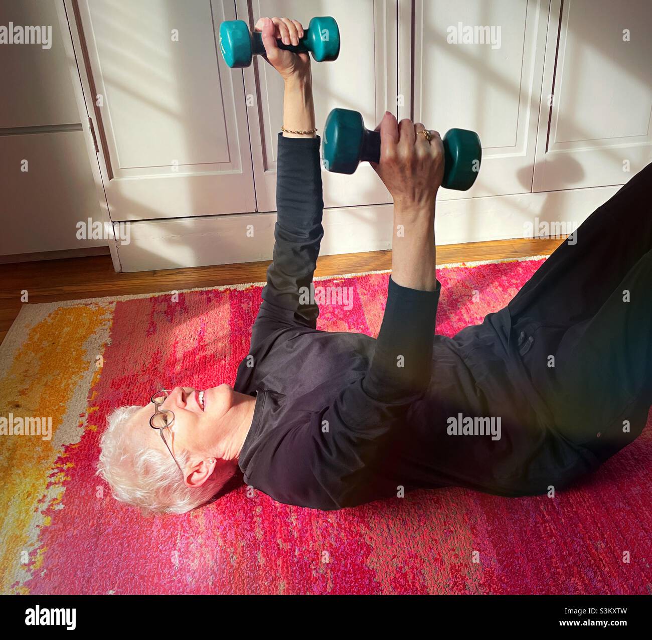 Senior woman exercising with dumbbells at home during the 2021 pandemic lockdowns, United States - Smartphone Captured Stock Image