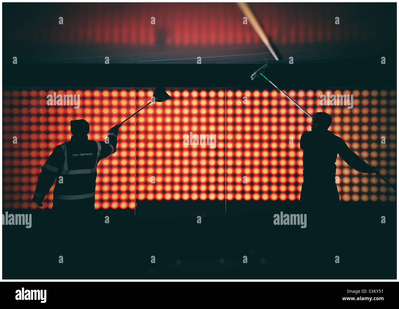 Two workers in Wembley cleaning a light display on the walkway to the Stadium - Smartphone Captured Stock Image