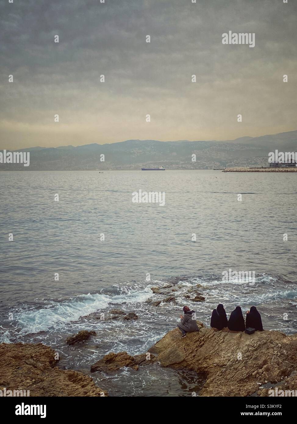 4 vailed women sitting on a rock on the Mediterranean Sea - Beirut Lebanon - Smartphone Captured Stock Image