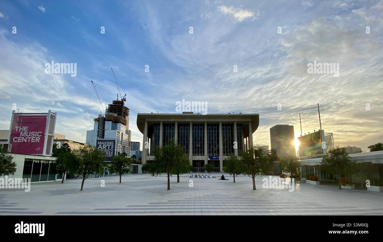 LOS ANGELES, CA, FEB 2021: exterior of the Dorothy Chandler Pavilion, home to the LA Opera at the Music Center in Downtown, with sun setting between nearby buildings and fountains in foreground Stock Photo