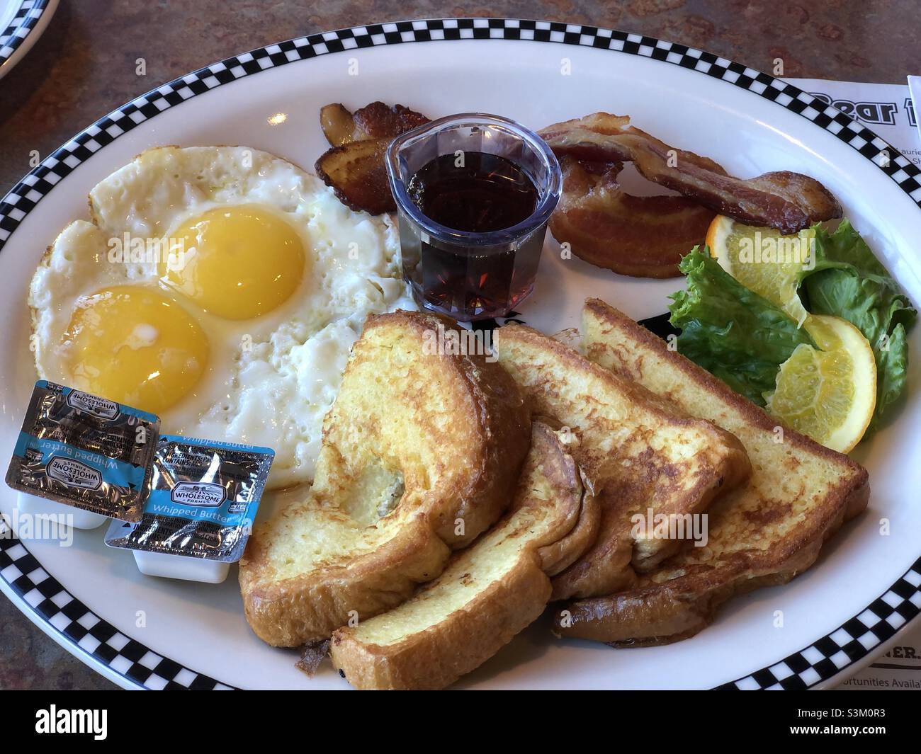 American breakfast. Eggs, bacon, French toast, butter and maple syrup