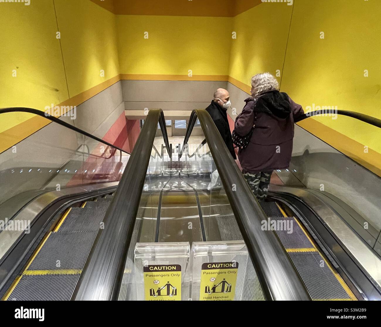 A couple of people going down on an escalator at the City Creek shopping complex in Salt Lake City, Utah, USA. - Smartphone Captured Stock Image