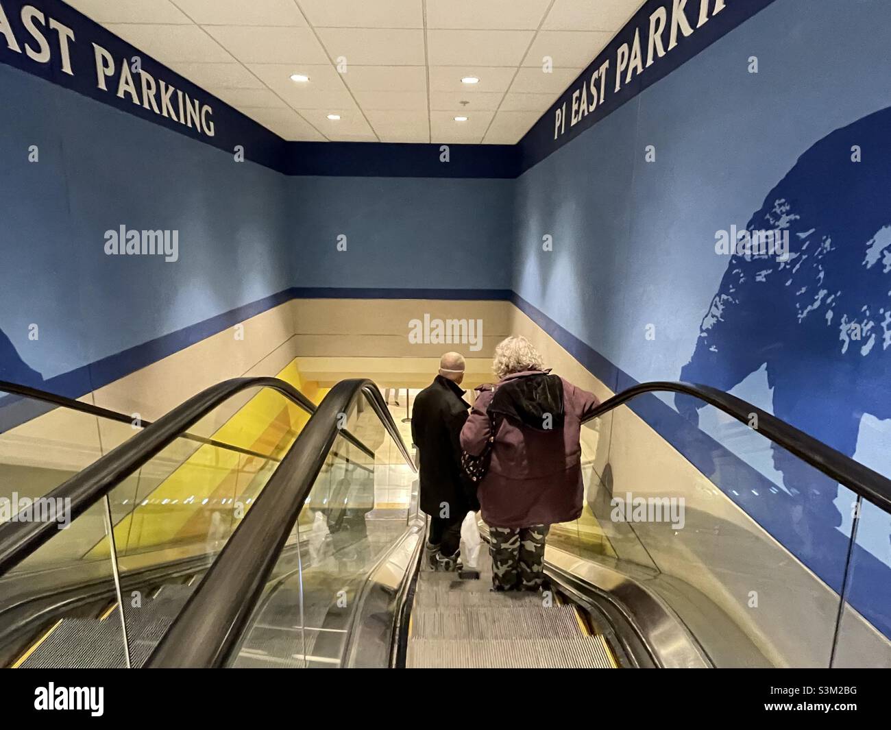 A couple riding the escalator down to the parking garage at the City Creek shopping center in Salt Lake City, Utah, USA. - Smartphone Captured Stock Image