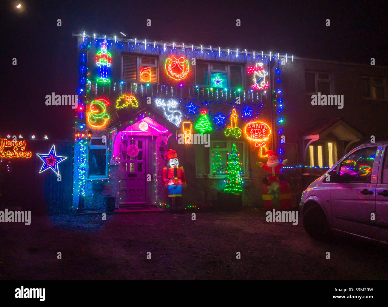 A house covered with many colourful Christmas lights and decorations at night. - Smartphone Captured Stock Image