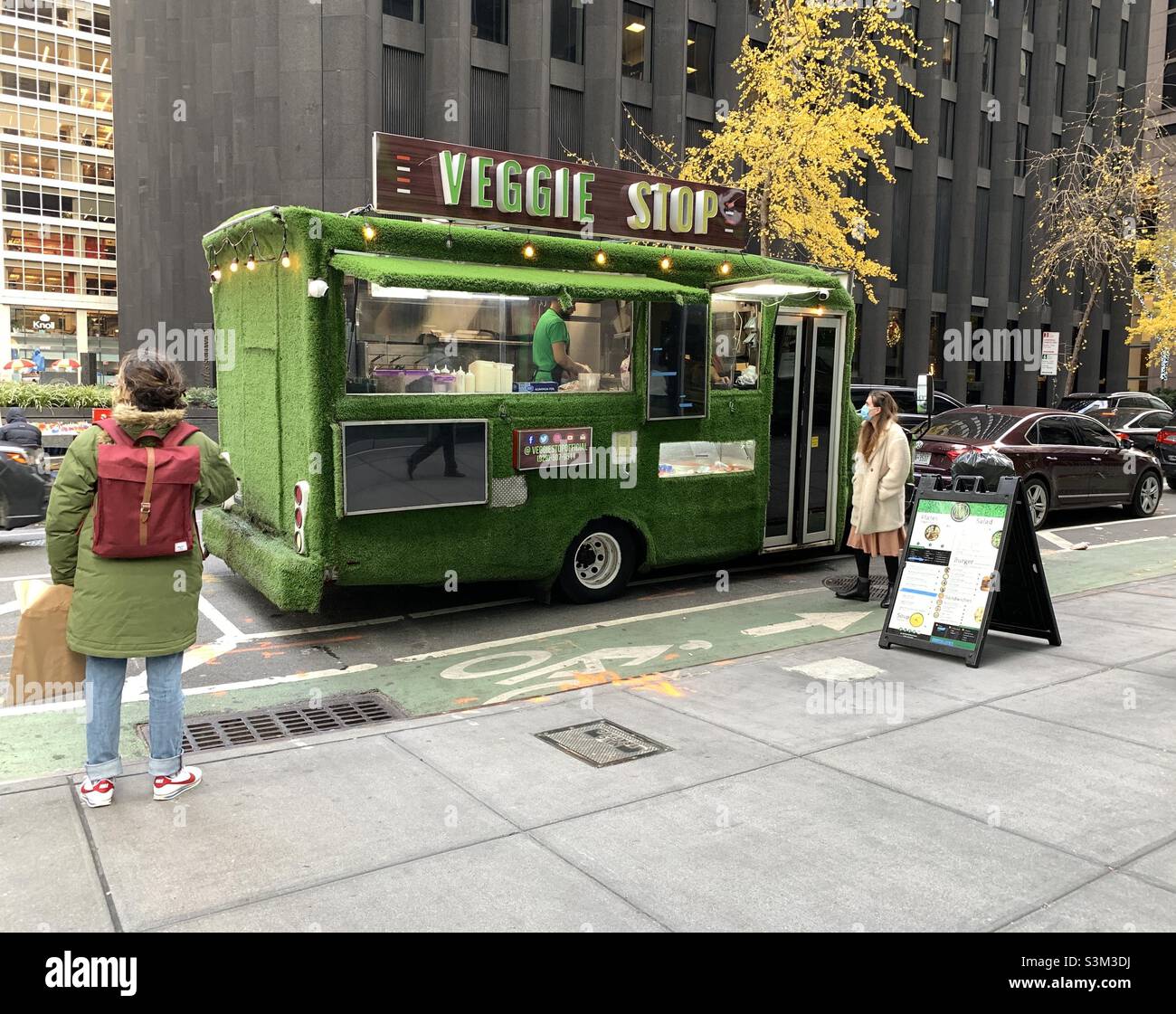 A woman standing looking at the window of veggie stop. - Smartphone Captured Stock Image