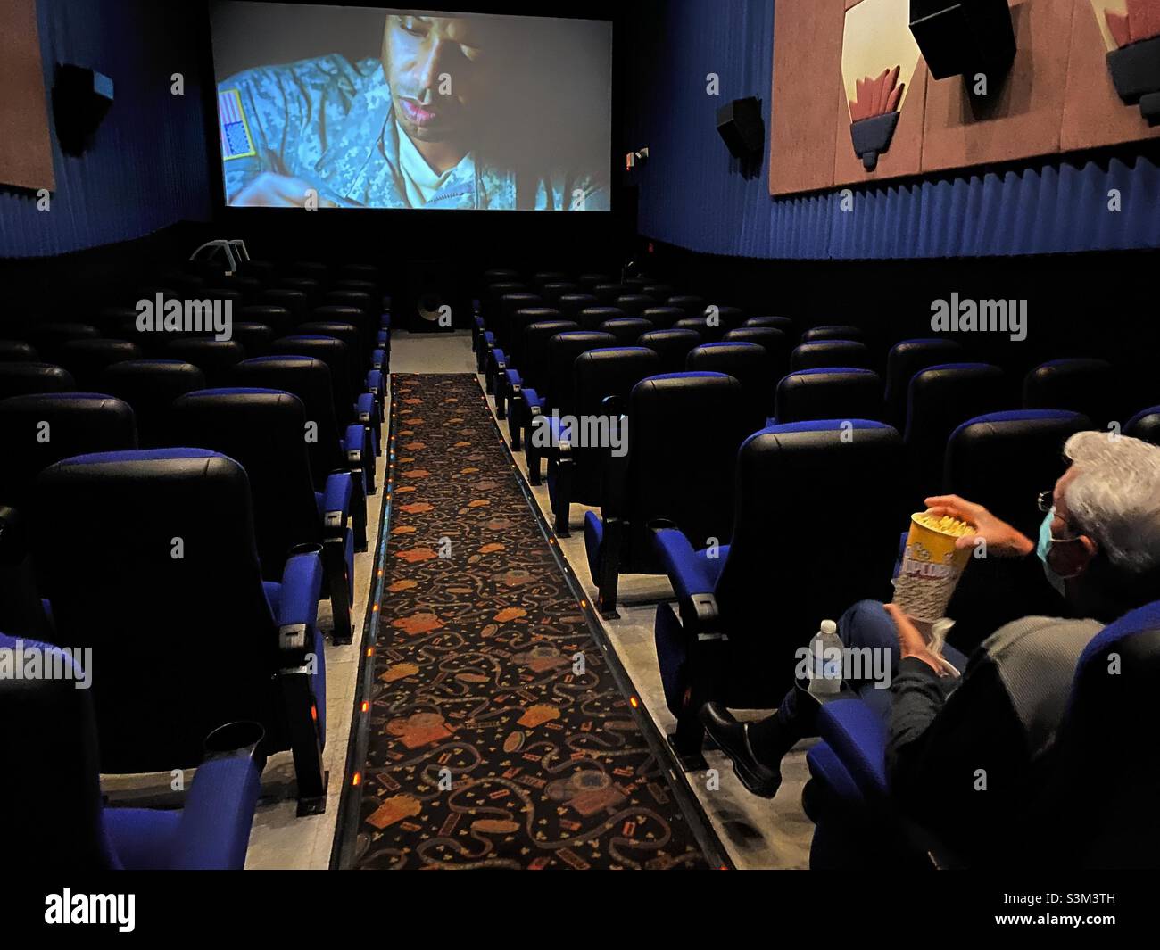 A single man sitting alone in a movie theater during the COVID-19 pandemic, 2021. - Smartphone Captured Stock Image