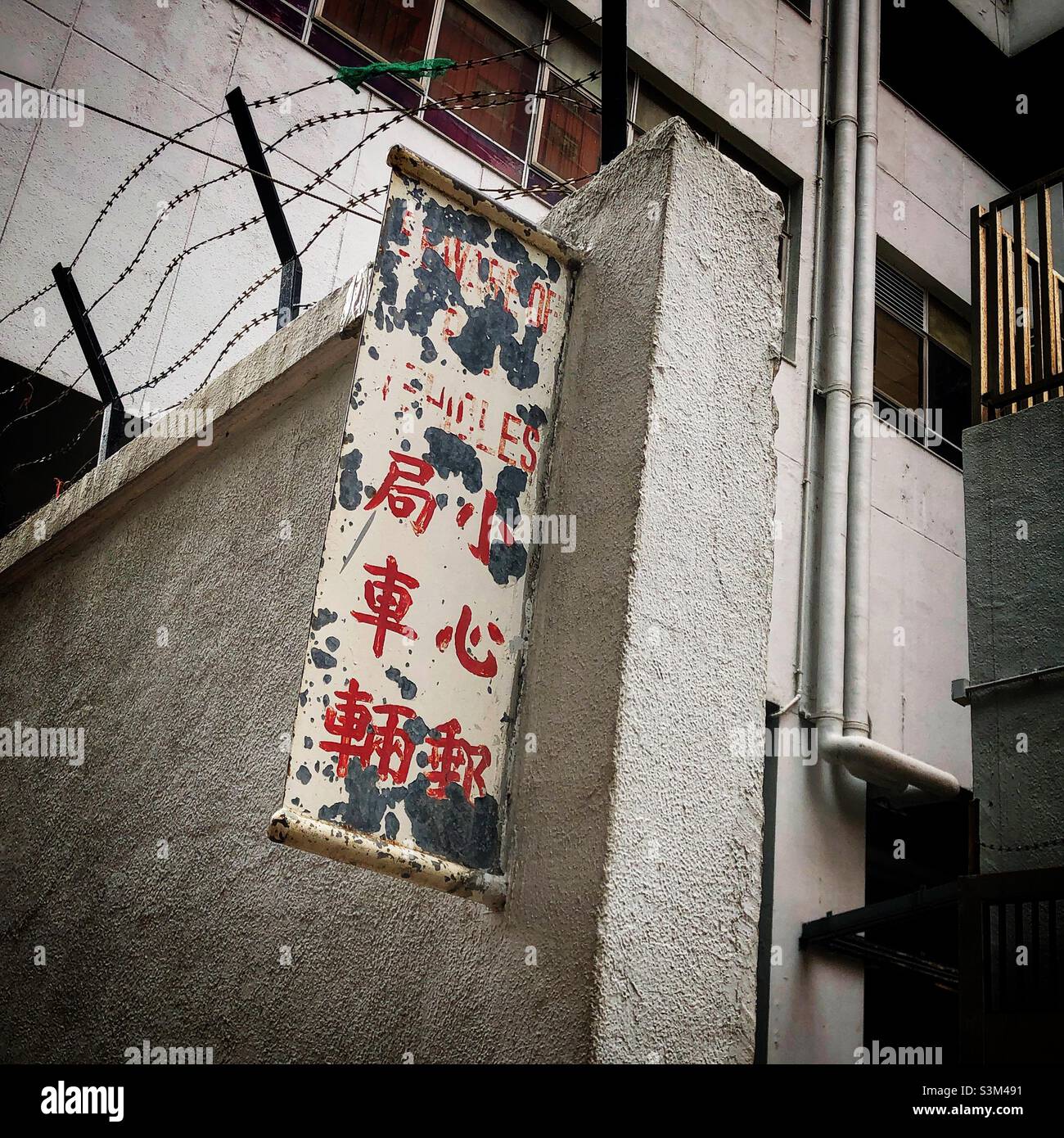 Faded and peeling bi-lingual painted metal cautionary sign, Mong Kok, Kowloon, Hong Kong - Smartphone Captured Stock Image