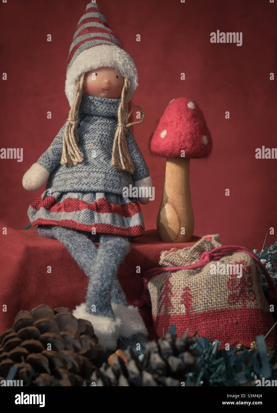 Red & grey themed Chris display, with doll in knitwear, felted mushroom, present sack and pine cones Stock Photo