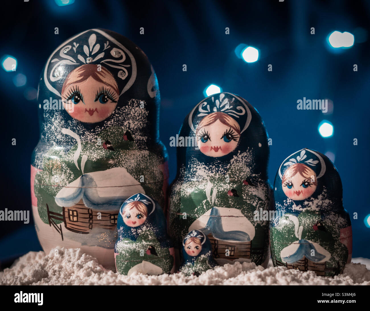 A set of wintery themed Russia dolls against a blue background with white lights - Smartphone Captured Stock Image