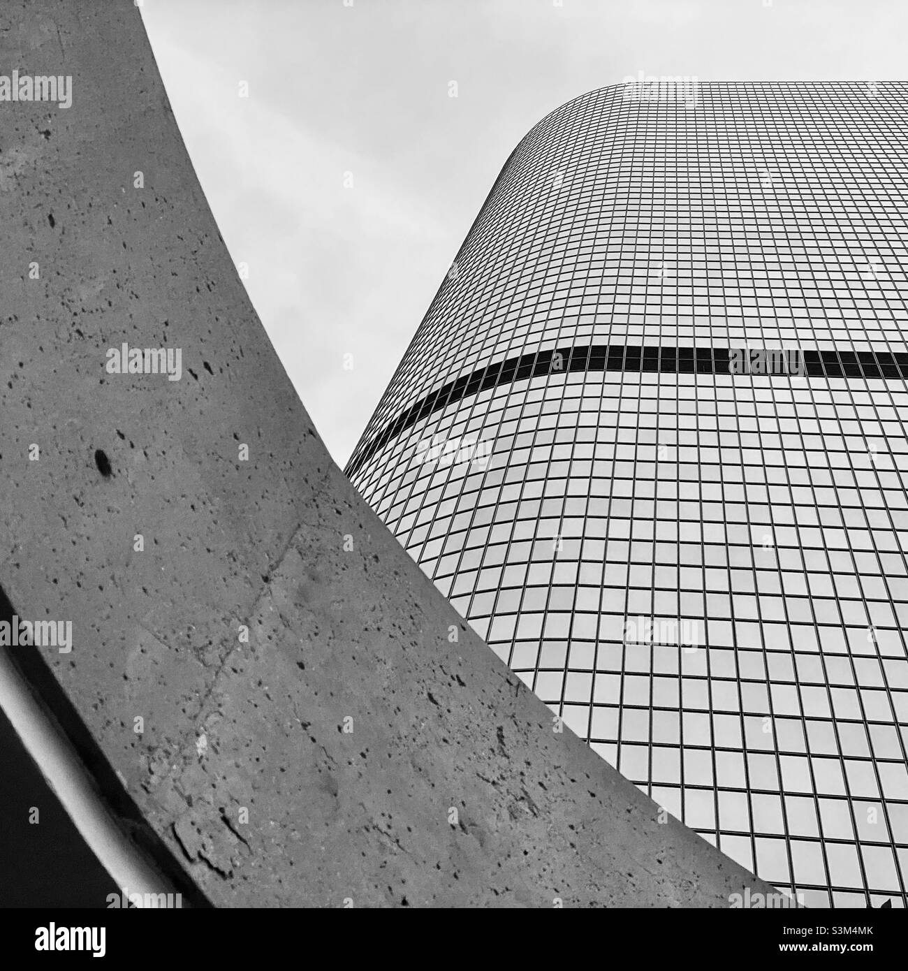 LOS ANGELES, CA, FEB 2021: looking up at curving, concrete architecture with California Plaza skyscraper rising behind, black and white - Smartphone Captured Stock Image