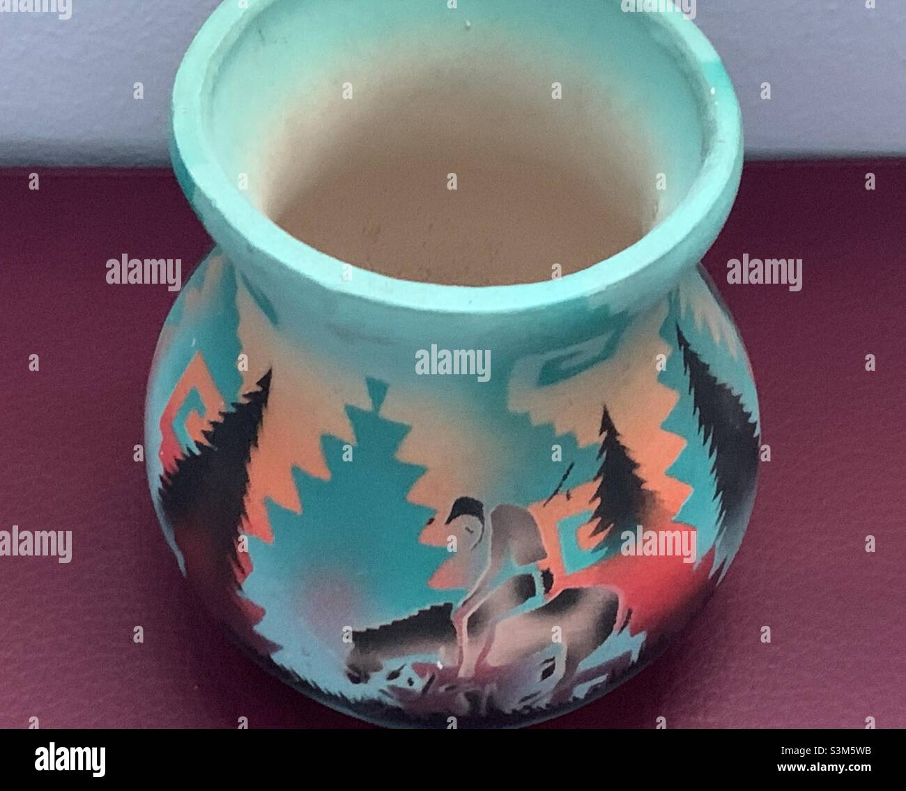Native American pottery shows wearied rider on a horse in a turquoise and orange southwestern styled wilderness. - Smartphone Captured Stock Image