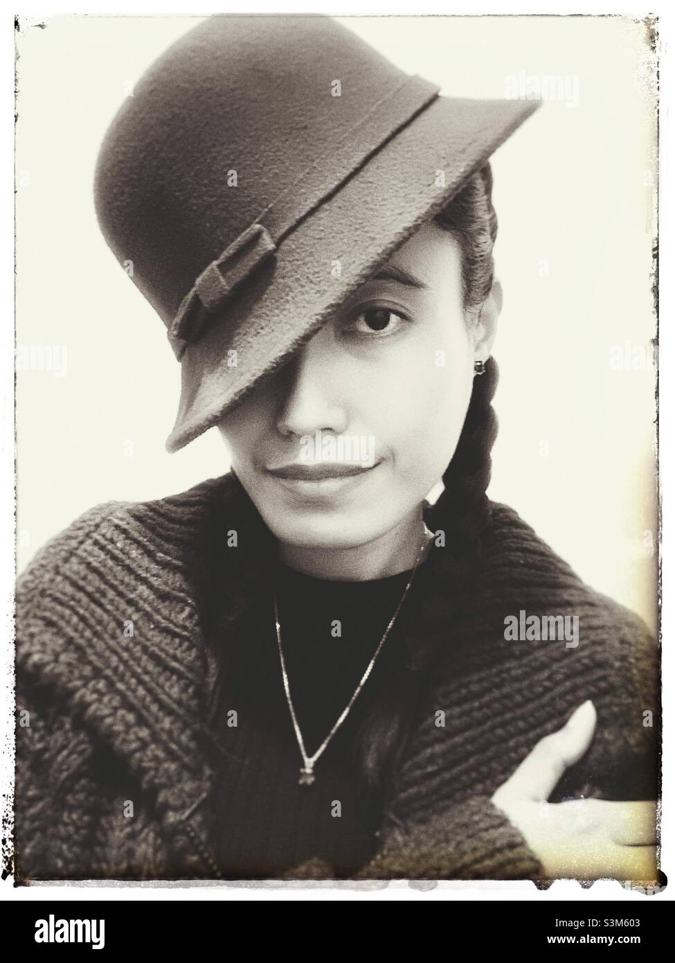 A woman’s portrait covering her one eye using the hat. Black and white with vintage effects. - Smartphone Captured Stock Image