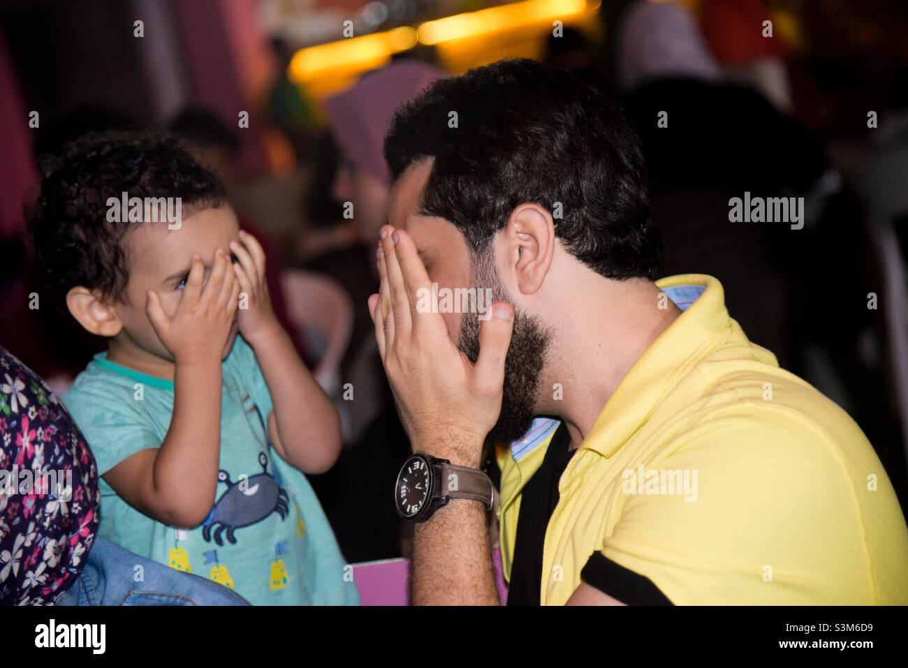 a child and an adult playing peek-a-boo Stock Photo