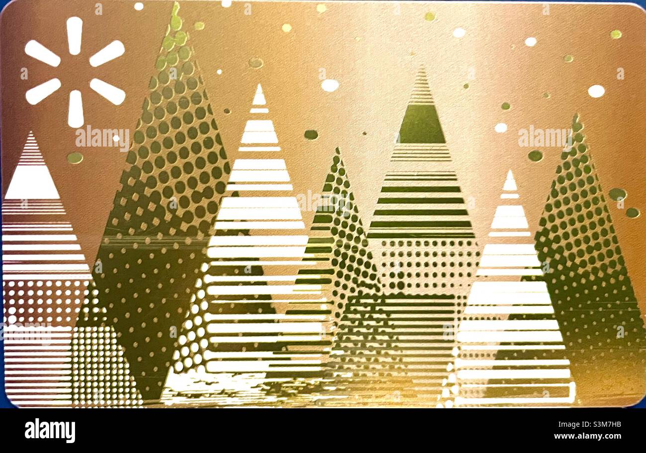 The front of a Walmart gift card during the Christmas season. The design is pleasant with a gold background, with many Christmas trees in shades of green and white in the foreground. - Smartphone Captured Stock Image