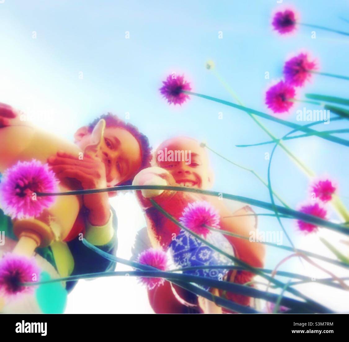 Children smiling with Chive flowers. - Smartphone Captured Stock Image