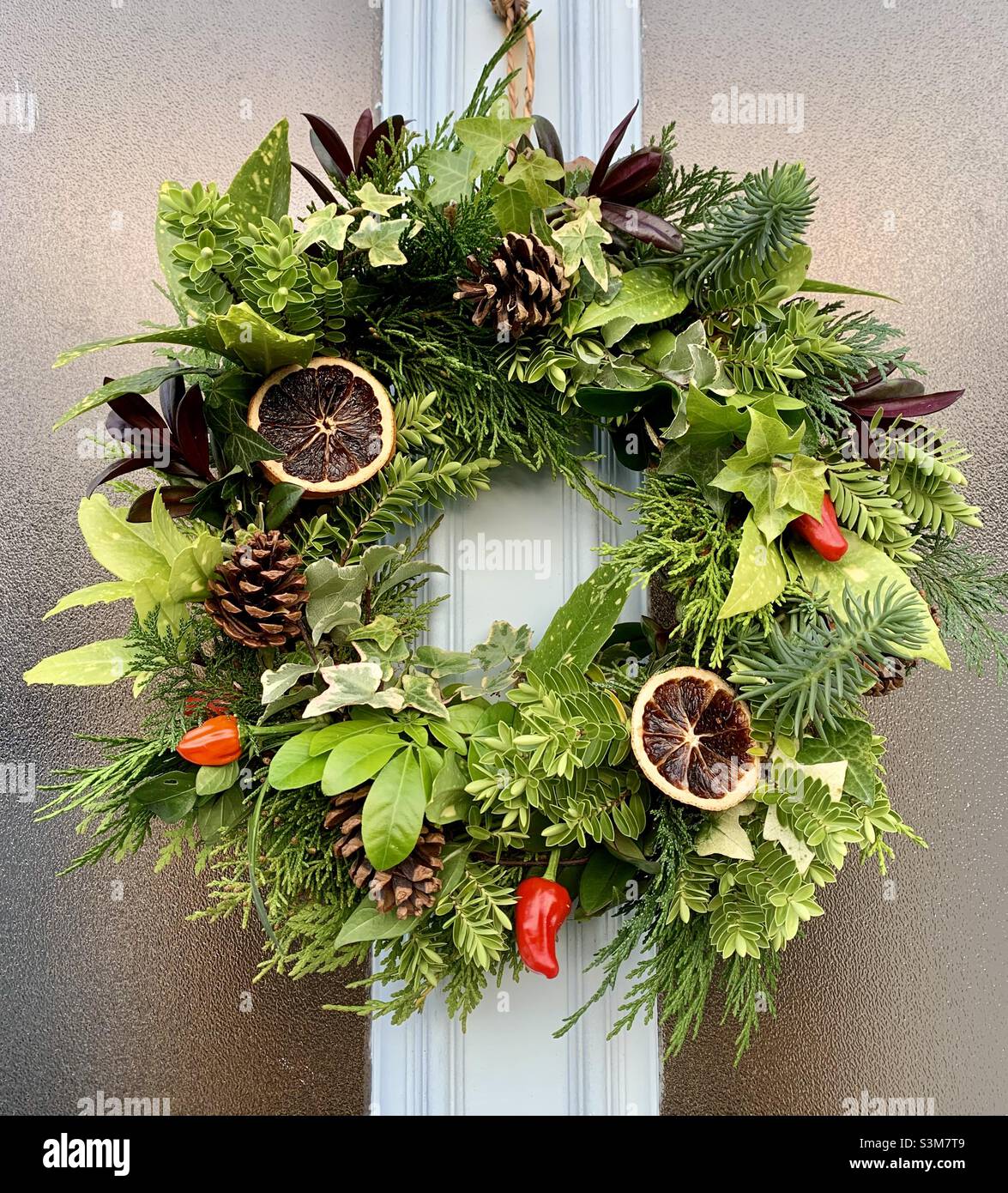 Homemade Christmas wreath with chillis and oranges on front door Stock Photo