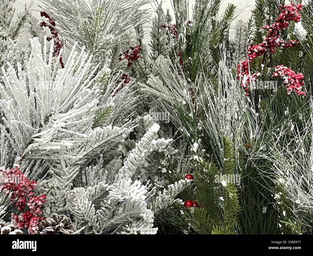 Christmas artificial floral arrangements being sold at a local Walmart in Utah, USA. Very seasonal with green pine needles, red berries and flocking to give it a frosted look. - Smartphone Captured Stock Image