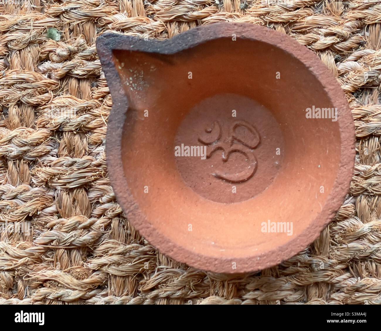 A simple mass produced clay lamp, Bearing an impressed mark Om, Such as might be used in a Hindu temple as a votive offering Stock Photo