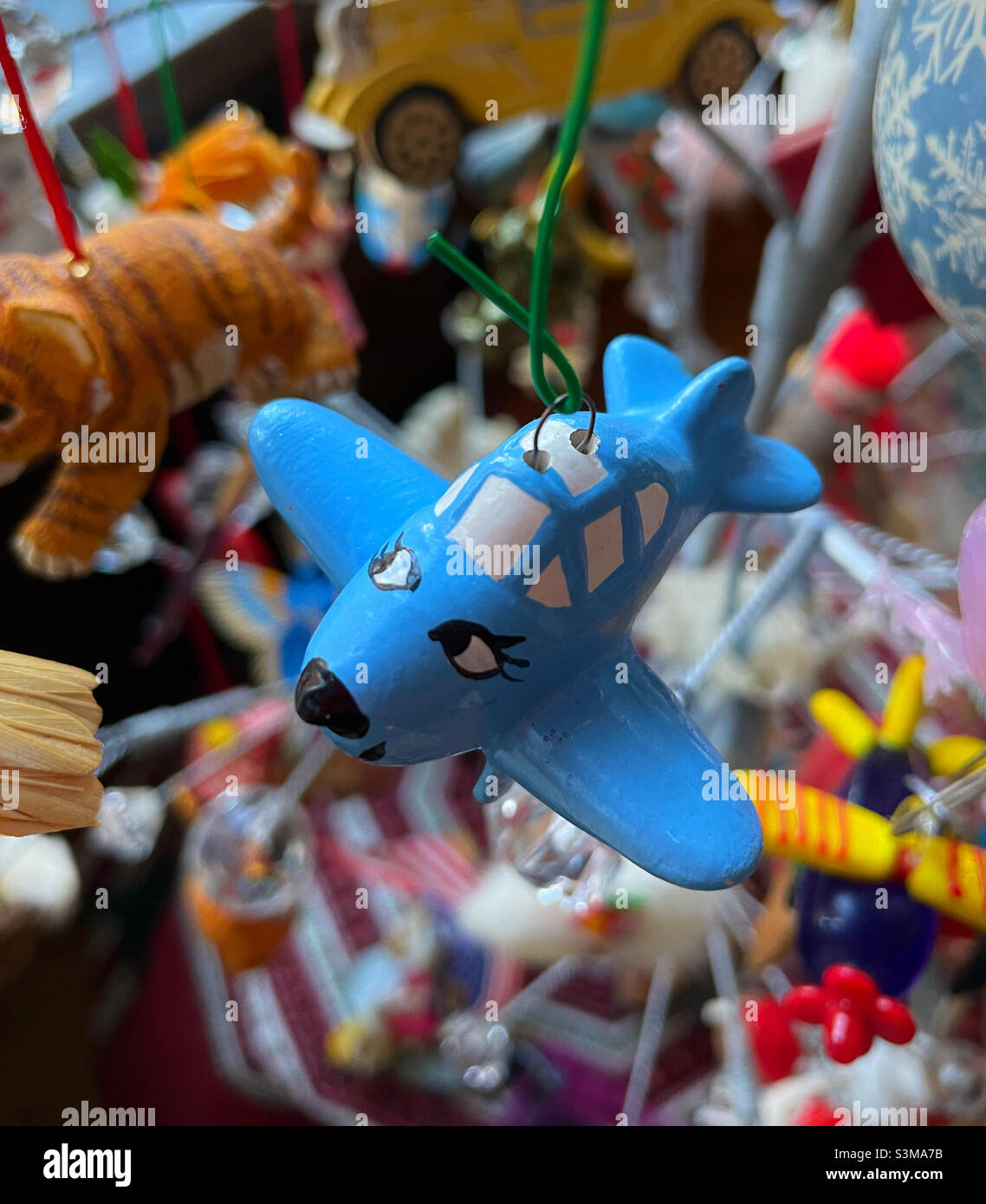 Close-up of a vibrant blue airplane ornament hanging on a Christmas tree during the holiday season in the United States, 2021 - Smartphone Captured Stock Image