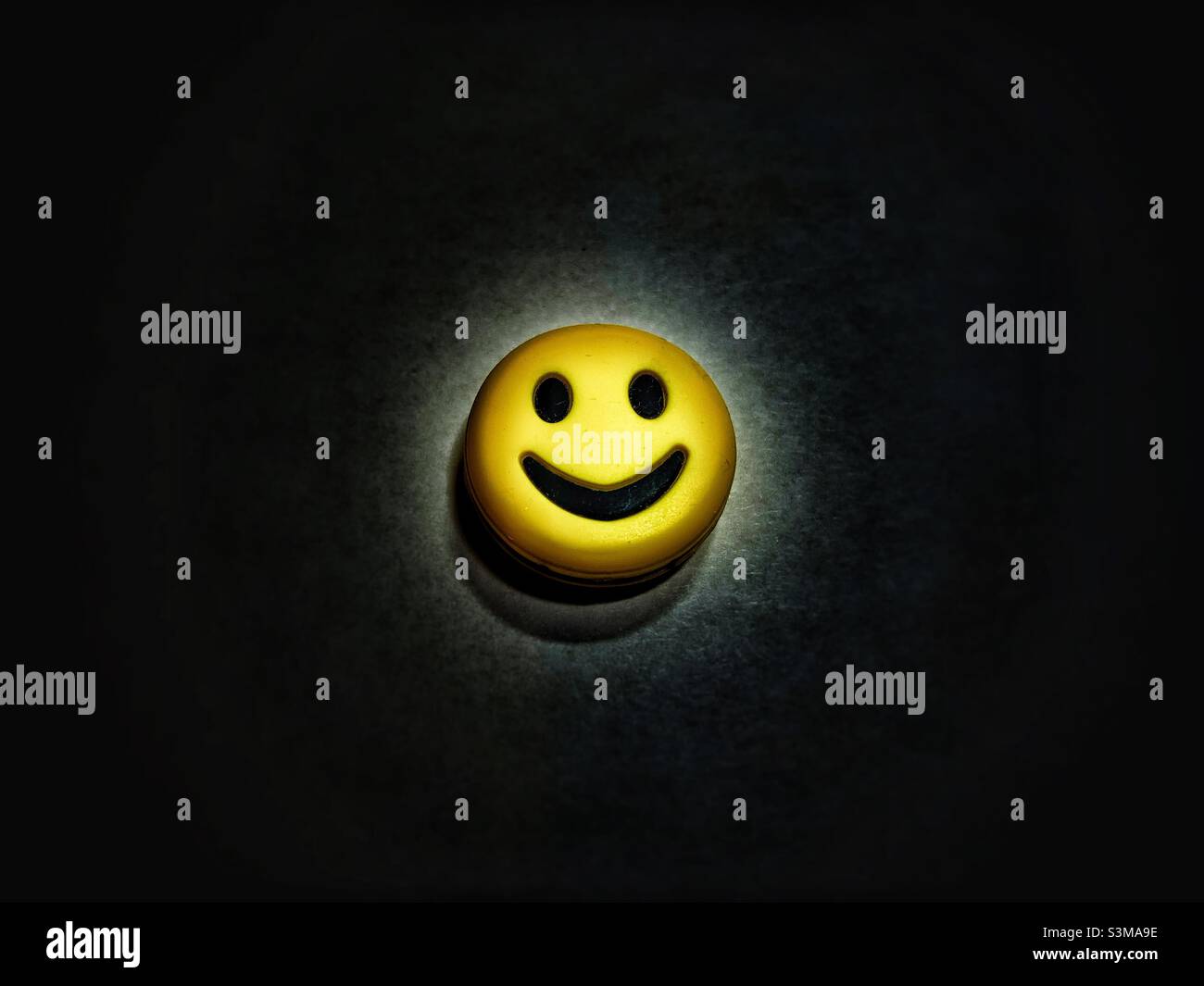 Yellow smiley face against black background. Stock Photo