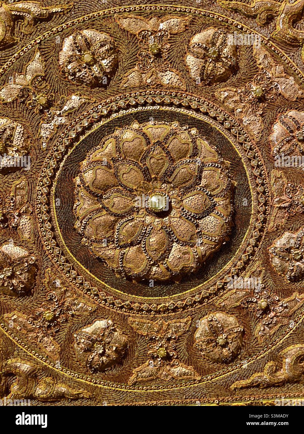 The centre section of a traditional Burmese embroidery showing a circular motif studded with jewels - Smartphone Captured Stock Image