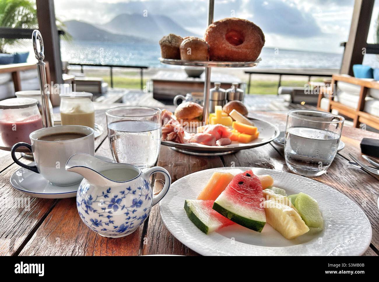 Breakfast table overlooking Nevis Island from St.kitts in the West Indies- showing fruit, pastries and coffee Stock Photo