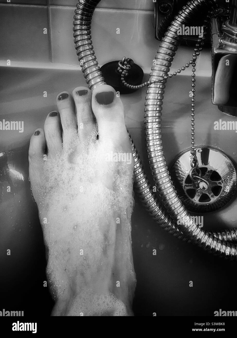 Foot with painted toenails in bath. Black and white photo. Stock Photo