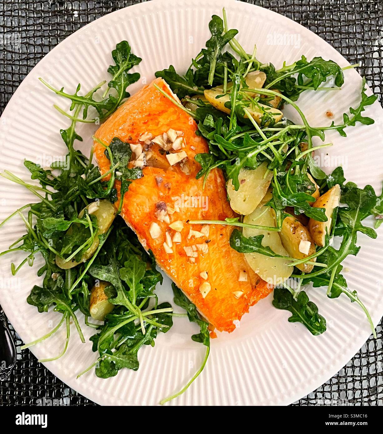 Flat lay of gourmet meal of braised salmon fillet on a bed of arugula and creamery potatoes, USA, 2021 - Smartphone Captured Stock Image