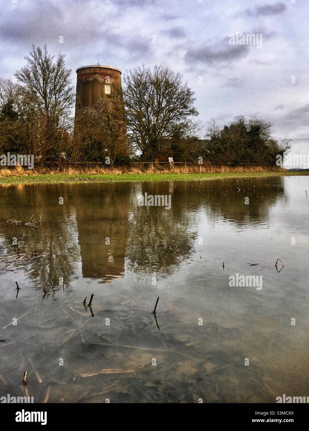 Stansfield mill tower reflected in water from flooding. Suffolk uk