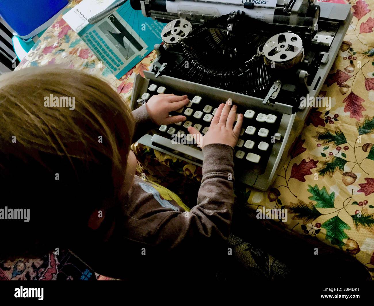 Today’s child, yesterday’s technology. A toddler presses a bunch of keys on a manual typewriter. A plaything, a toy, not a functional machine today, Ontario, Canada - Smartphone Captured Stock Image