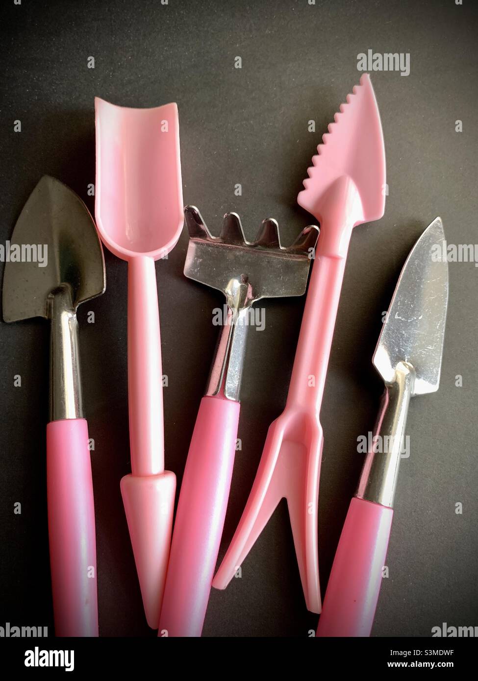 Five pink mini or small gardening tools against black background. - Smartphone Captured Stock Image