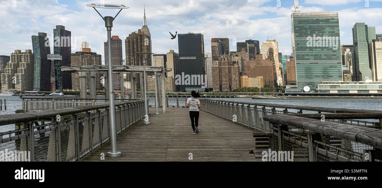 Young woman in her twenties jogging bi the Piers over the East River, Gantry Plaza State Park, in Long Island City, New York. - Smartphone Captured Stock Image