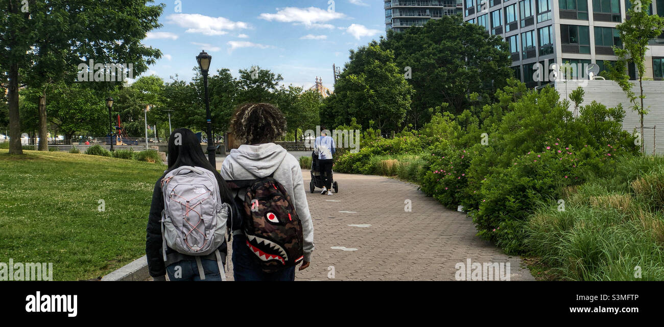 Teenagers walking by the Hunters Point Community Library in Long Island City on a sunny warm day - Smartphone Captured Stock Image