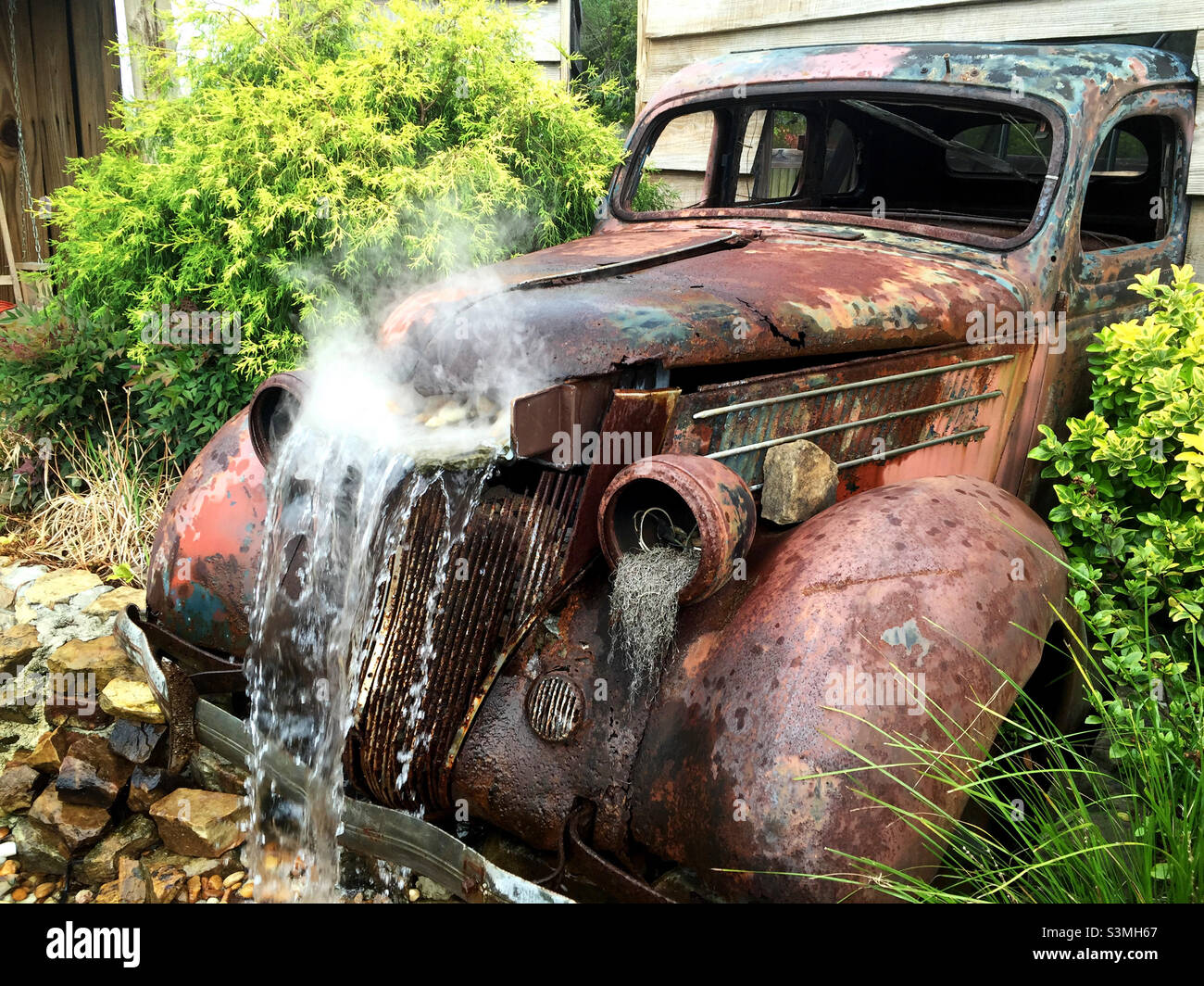 Antique rusty truck converted to a garden water fountain. Stock Photo