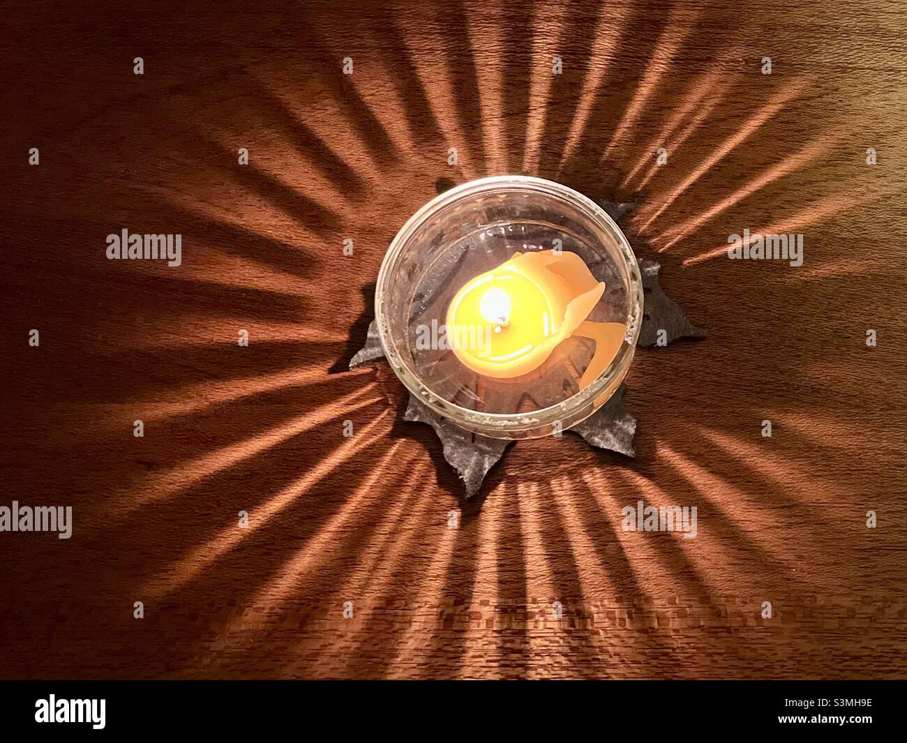 Beautiful sun like pattern created by a candle in a glass holder Stock Photo
