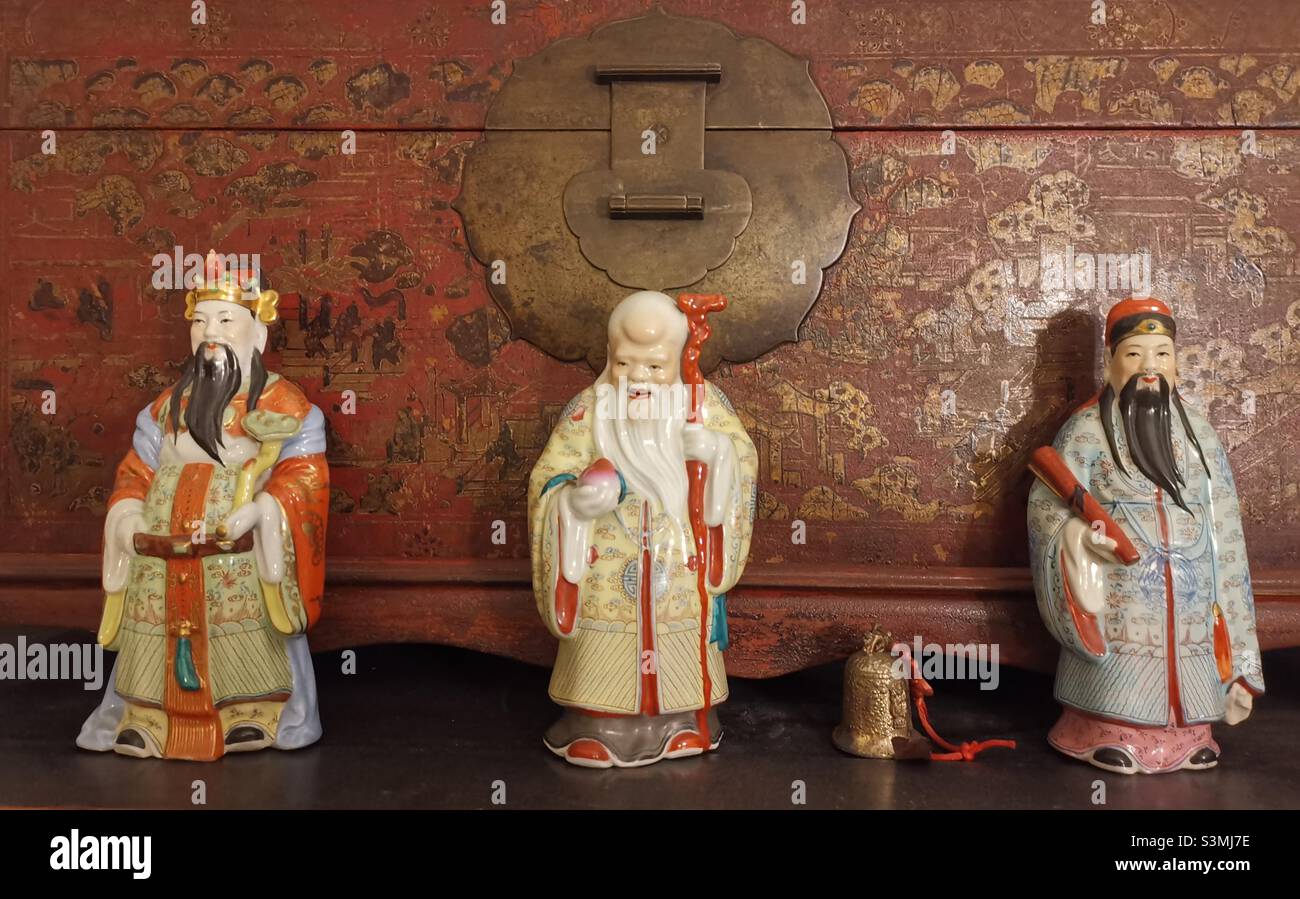 Statues of the three stars ( Sanxing ) deities with a traditional Chinese chest box as a background. - Smartphone Captured Stock Image