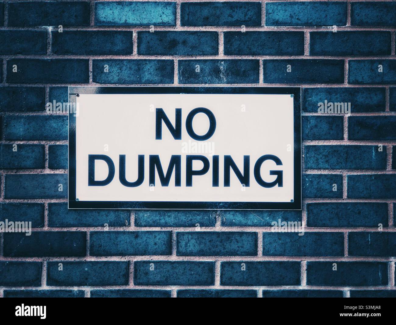 No Dumping sign on a brick wall in a car park. Stock Photo