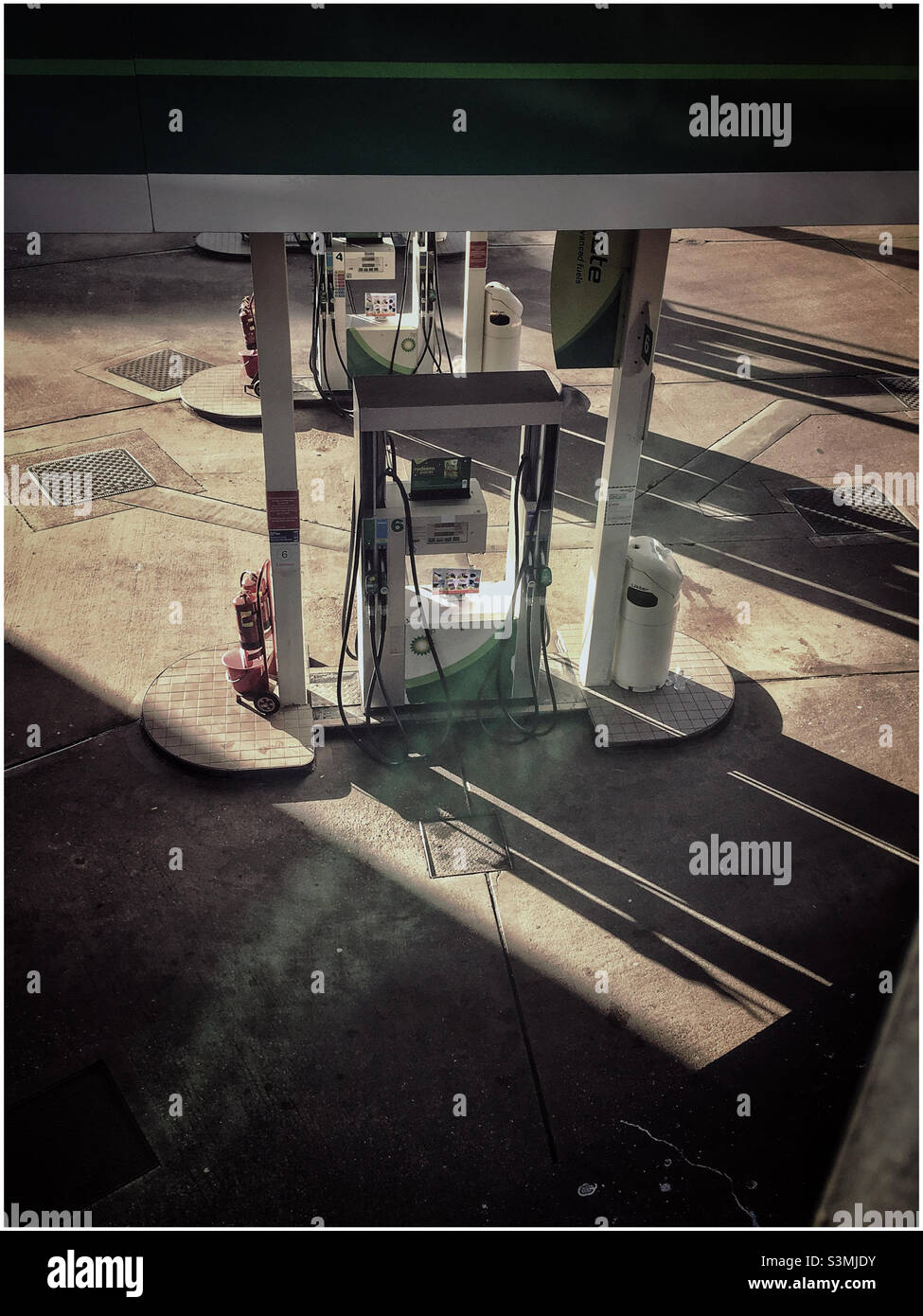 Petrol pump casting long shadows on the forecourt - Smartphone Captured Stock Image